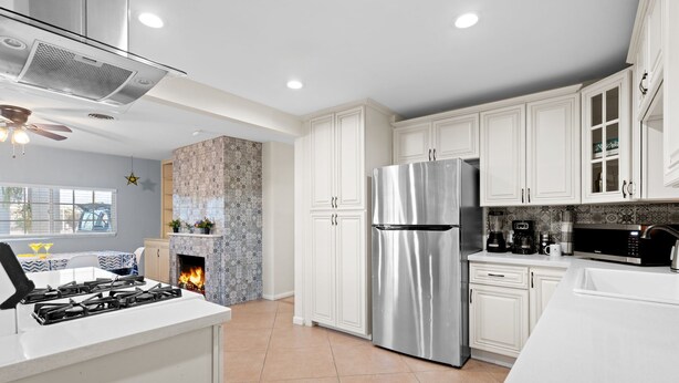 A modern kitchen with white cabinets, a stainless steel refrigerator, a gas stove, and a microwave. - Moroccan Hacienda Retreat- By Festival Grounds (Indio)