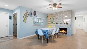 A dining area with a table set for four, a fireplace, and a ceiling fan. - Moroccan Hacienda Retreat- By Festival Grounds (Indio)