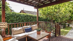 A covered outdoor deck with a sofa, a table, and potted plants. - 3-bedroom Burbank Pool home close to studios and a Park across the street! (Burbank)