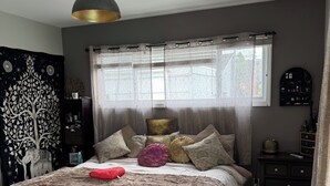 A bedroom with a bed, a bedside table, a lamp, a window with curtains, and a wall-mounted shelf. - 3-bedroom Burbank Pool home close to studios and a Park across the street! (Burbank)