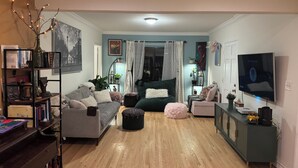 A living room with a sofa, ottoman, TV, bookshelf, and a dining area with a table and chairs. - 3-bedroom Burbank Pool home close to studios and a Park across the street! (Burbank)