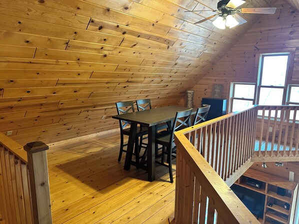 Un interno in legno con un tavolo da pranzo e sedie, una ventola a soffitto e una vista dalla finestra.