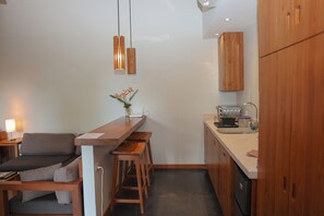 A compact kitchen with wooden cabinets, a countertop, and a bar area. - Garden Heights Studio at Taru Rentals (Montezuma)