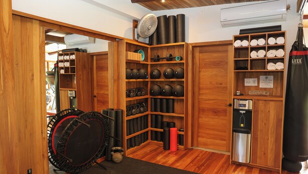 A gym with wooden cabinets, kettlebells, a punching bag, and a water dispenser. - Garden Heights Studio at Taru Rentals (Montezuma)