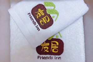 Toalla blanca con logotipos y texto bordados que indican 'Friends Inn'.