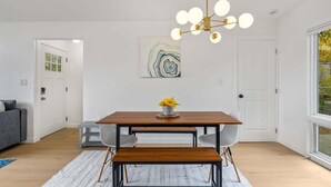 Un comedor moderno con una mesa de madera, banco y una araña.