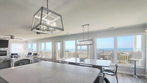 Een ruime keuken met een groot schiereiland, een eethoek met uitzicht en een balkon dat uitkijkt op de oceaan.