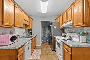 Una cucina con mobili in legno, un forno a microonde rosa, un piano cottura e un frigorifero.