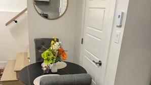 Comedor con una mesa redonda, una silla tapizada en gris y un jarrón con flores.