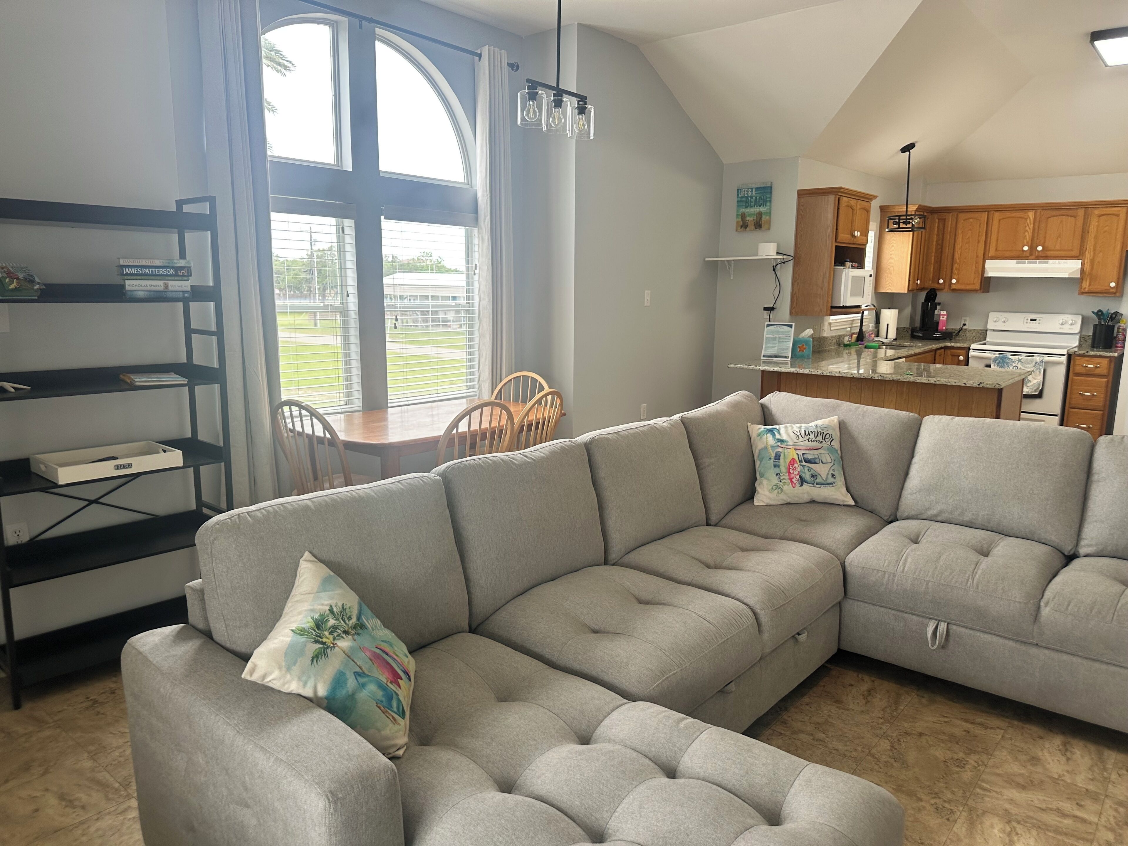 A modern living room with a sectional sofa, dining table, and kitchen area.