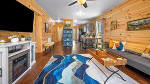 Un intérieur en bois avec une télévision, une cheminée, un canapé et un ventilateur de plafond.