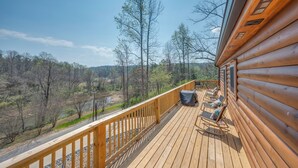 Une terrasse en bois, aménagée avec du mobilier d’extérieur, qui offre une vue sur une zone boisée.