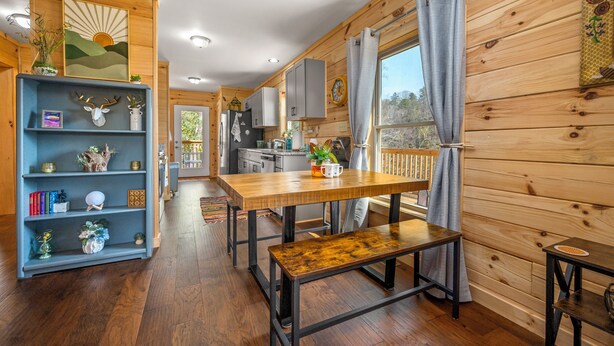 Un intérieur en bois comprenant un coin repas, une cuisine et une bibliothèque.