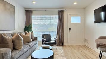 A modern living room with a sofa, a coffee table, a chair, and a TV.