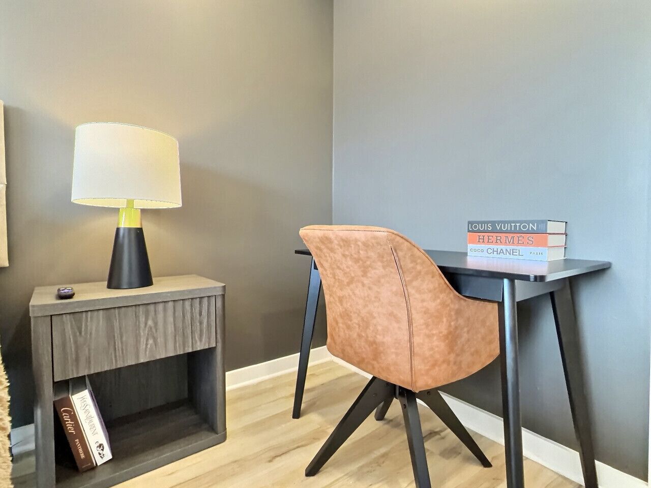 A modern room with a wooden side table, a lamp, a chair, and a stack of books on a small table.