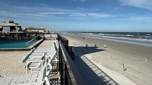 Blick auf einen Strand mit Poolbereich, Liegestühlen und einem Steg.