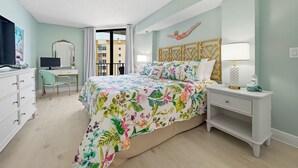Une chambre avec un lit, un bureau, une chaise, une télévision et un balcon.