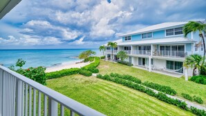 A beachfront hotel with a two-story structure, a balcony, and a view of the ocean. - 7 Mile Beach | Soft Sand, Epic Sunset Views & Shipwreck Snorkel (Grand Cayman)