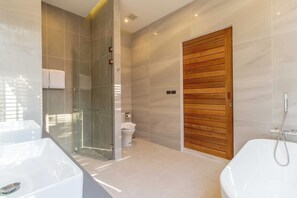 Un baño moderno con cabina de ducha de vidrio, puerta de madera y bañera blanca.