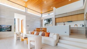 A spacious living area with a sofa, coffee table, and a TV mounted on the wall. - New Prime Location Near Boat Avenue V306 (Choeng Thale)