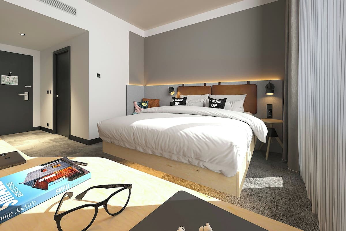 Una habitación de hotel moderna con una cama grande, mesitas de noche, un escritorio y una silla.