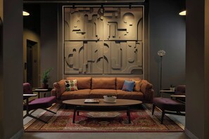 A modern lounge area with a brown leather sofa, a coffee table, and patterned rugs. - Moxy Belgrade Skadarlija (Belgrade)