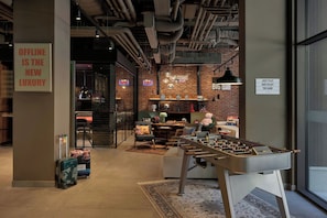A modern lounge area with a foosball table, seating, and a brick wall. - Moxy Belgrade Skadarlija (Belgrade)