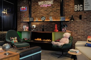 A cozy living room with a fireplace, comfortable seating, and a neon sign that reads 'WELCOME to Belgrade.'
