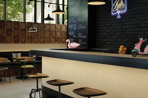 Un espace bar avec un menu écrit à la craie, des meubles en bois et un panneau lumineux au néon.