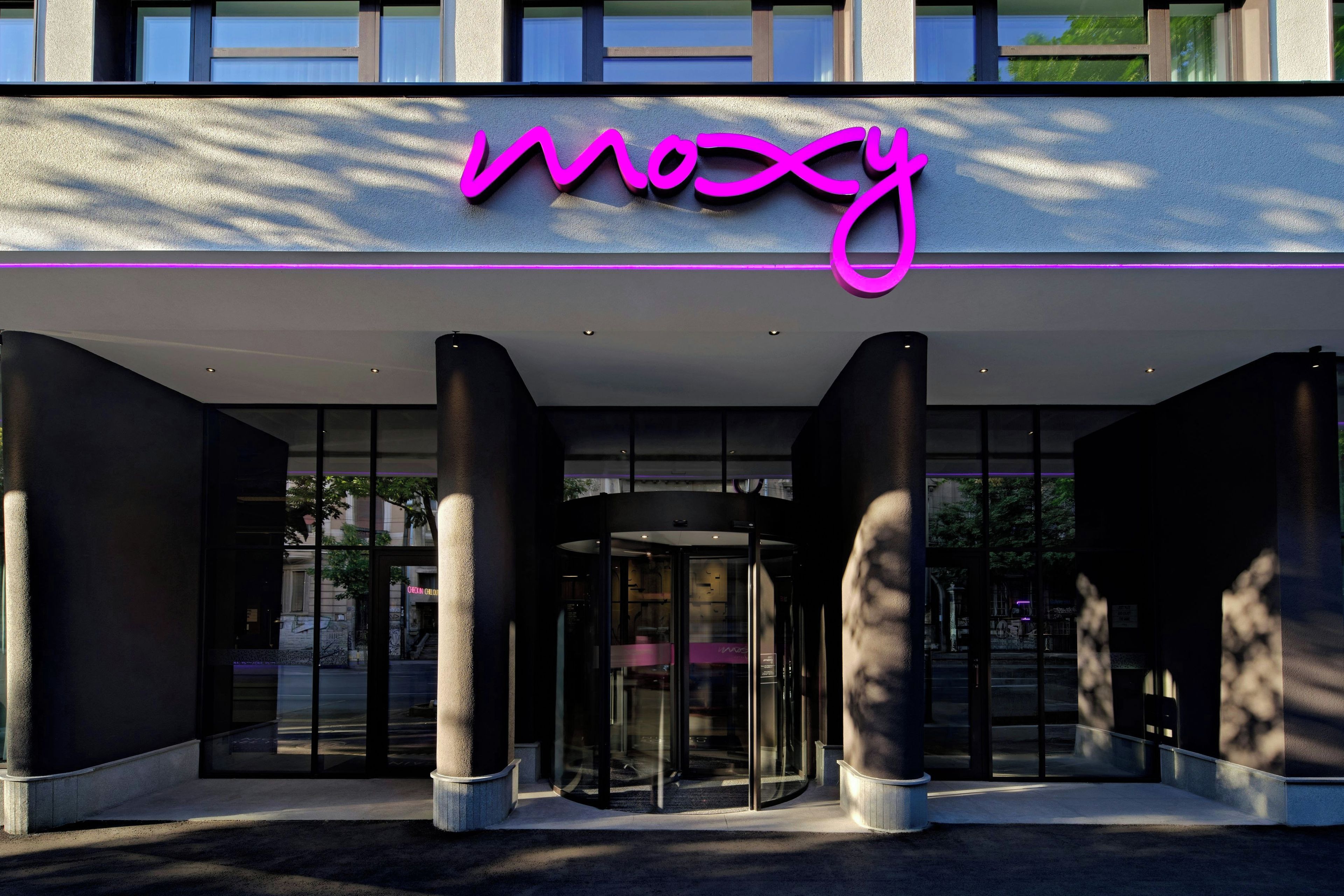 A building entrance with a glass revolving door and a neon sign above.