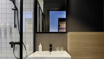 Une salle de bain moderne avec un lavabo blanc, une douchette à main et un miroir au-dessus du lavabo.