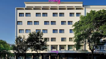 Un hôtel à plusieurs étages, doté d’une façade plate, de nombreuses fenêtres et d’une enseigne lumineuse au néon sur le toit.