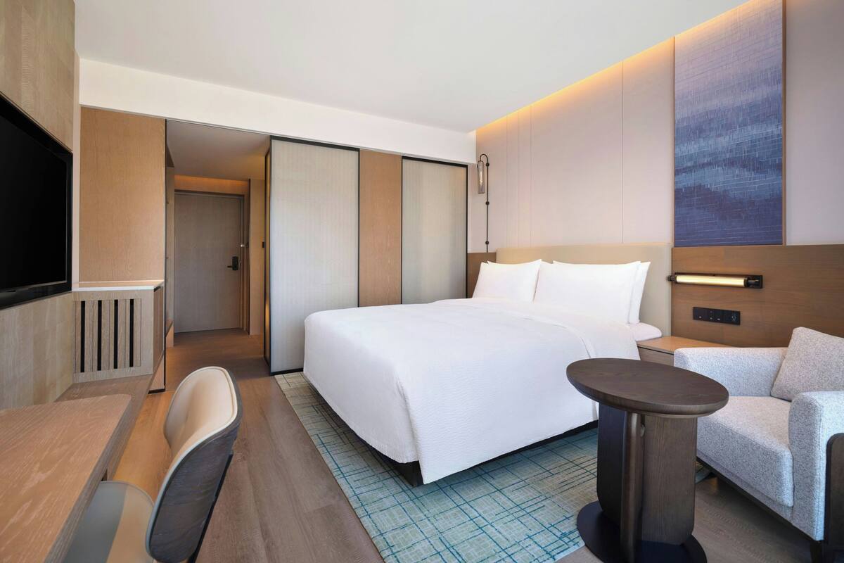 Een moderne hotelkamer met een groot bed, een zithoek met een tafel en een televisie.