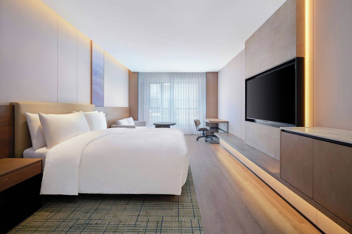 Een moderne hotelkamer met een groot bed, een bureau, een stoel en een televisie.