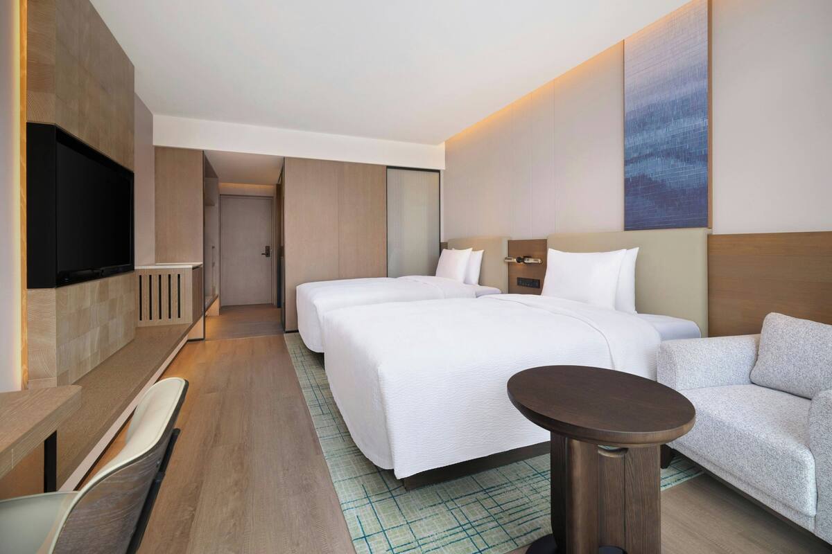 Een hotelkamer met een groot bed, een televisie, een bank en een kleine tafel.