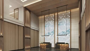 Eine moderne Lobby mit Holzvertäfelung, zwei Empfangstresen und einem großen Fenster mit Blick auf die Stadt.