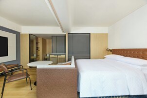Una habitación de hotel moderna con una cama, un escritorio, una silla y un televisor.