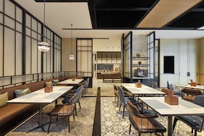 A modern restaurant with high tables and booths, a kitchen in the background, and a patterned floor. - Four Points By Sheraton Rizhao Central Activities Zone (Rizhao)