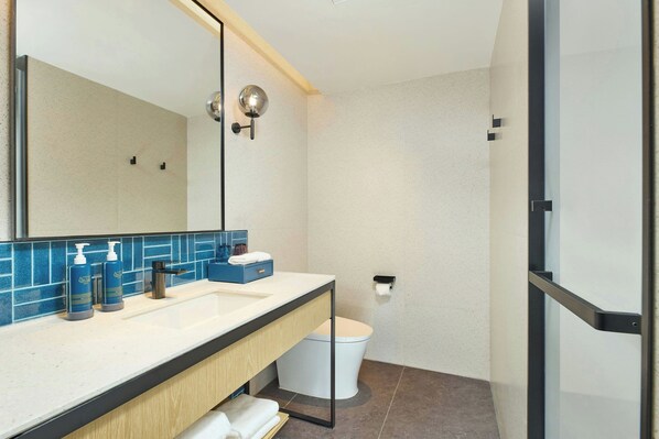 A modern bathroom with a large mirror, a sink with a soap dispenser, and a toilet. - Four Points By Sheraton Rizhao Central Activities Zone (Rizhao)