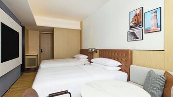 A hotel room with a large bed, a sofa, a dining table, and a TV.