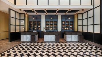 A lobby with a checkered floor, two reception desks, and a wall with display cabinets.