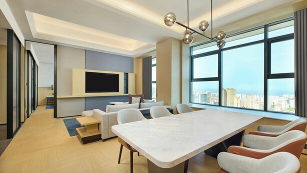 Une salle de conférence moderne, dotée d’une grande table, de sièges confortables, d’un téléviseur fixé au mur et de grandes fenêtres offrant une vue sur la ville.