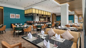Un restaurant avec des tables dressées pour le service, un bar et un espace salon avec des fauteuils confortables.
