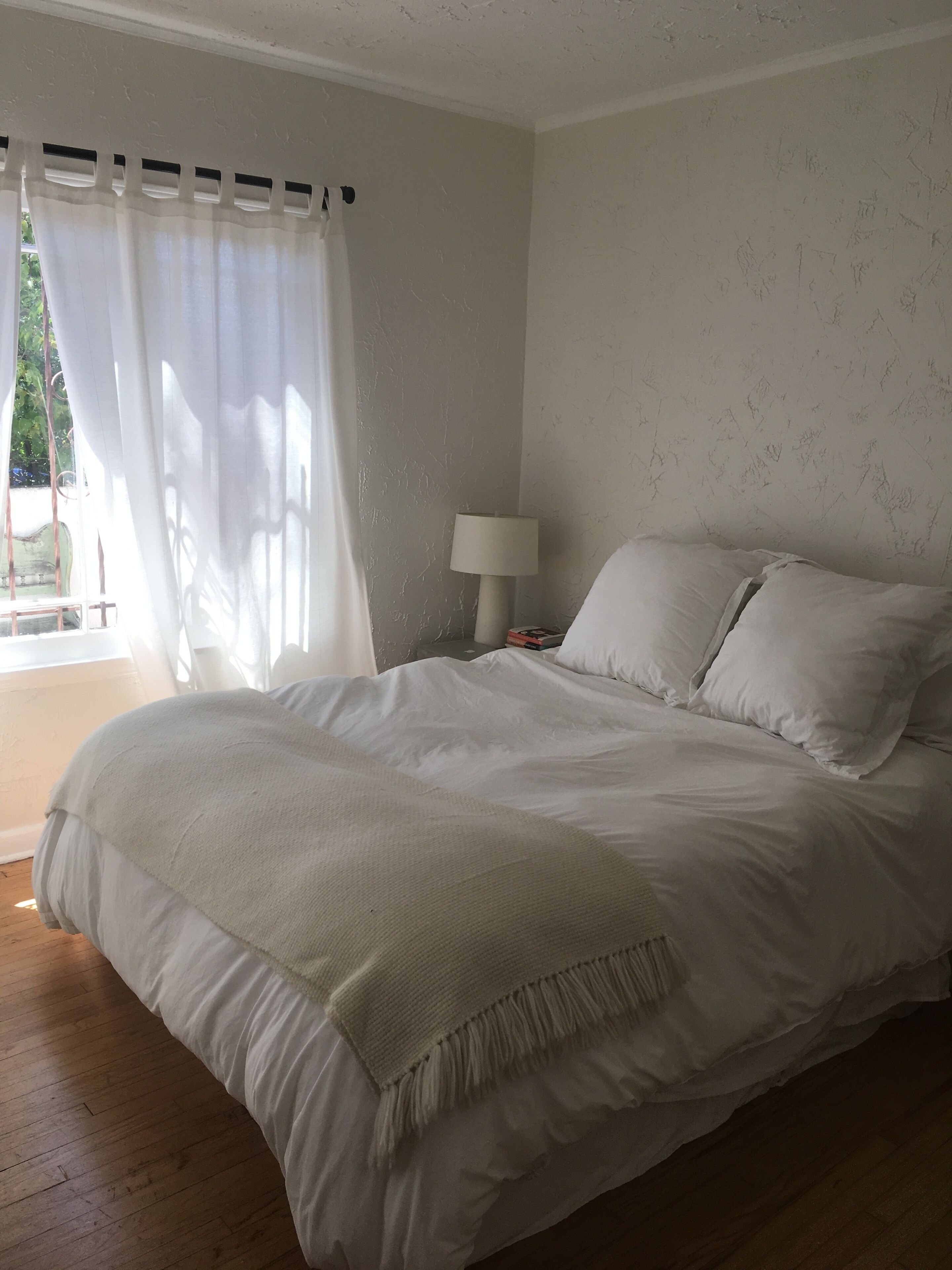 A bedroom with a bed, a lamp, and a window with curtains.
