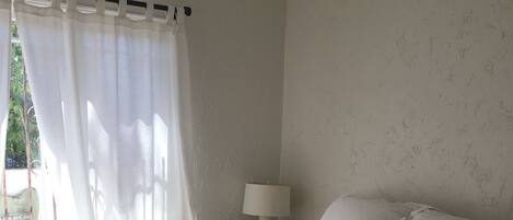 A bedroom with a bed, a lamp, and a window with curtains.