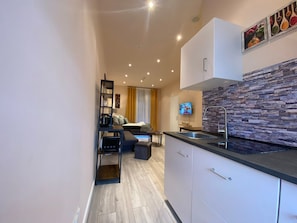 A modern kitchen with a stone backsplash, a built-in oven, and a dining area with a sofa and table. - Apartment Sleeps 3 with Parking and Garden (Koblenz)