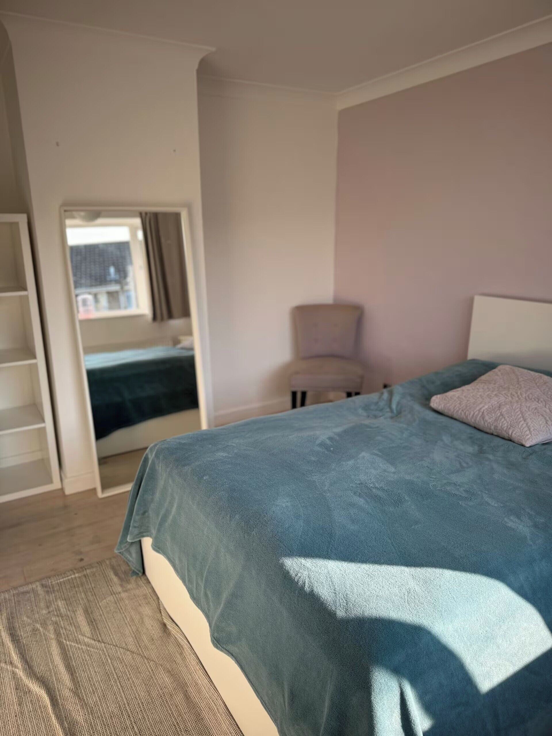 A bedroom with a bed, a chair, a window, and a wardrobe.