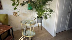Une pièce avec un plancher en bois, une table à manger, une plante en pot, un plateau décoratif en métal et une porte.