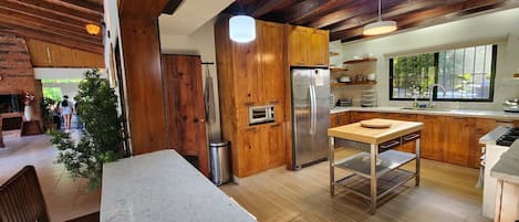 Una cocina moderna con armarios de madera, un refrigerador de acero inoxidable y un comedor con mesa y sillas.