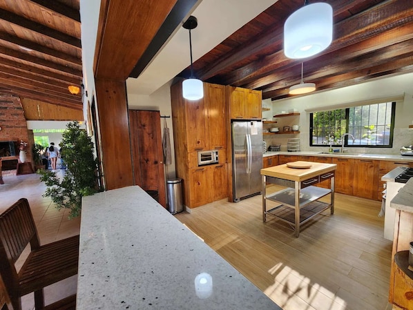 A modern kitchen with wooden cabinets, a stainless steel refrigerator, and a dining area with a table and chairs.